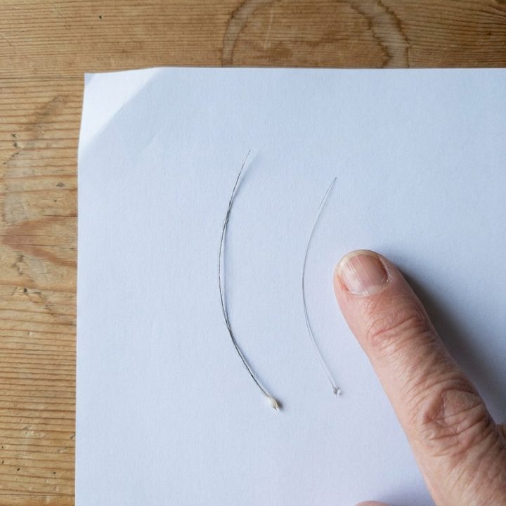 Two hairs on white paper, one thick, one fine