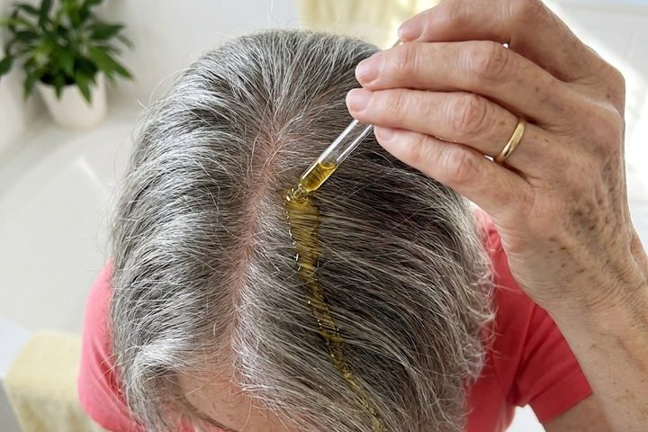 A dropper of serum landing on the hair rather than the scalp